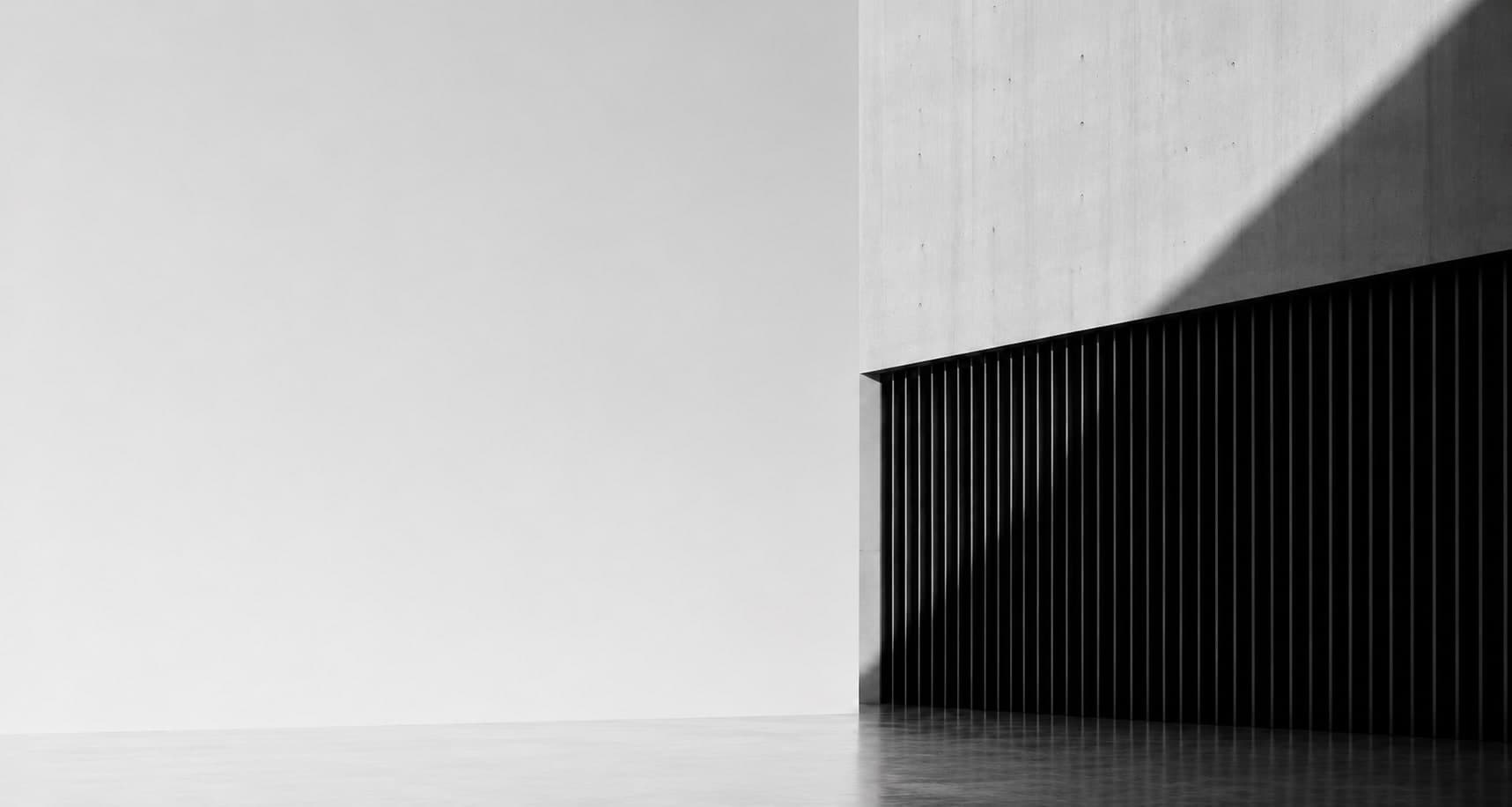 Concrete wall with dark vertical louvres and a soft floor reflection